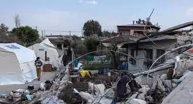 Ein altes und durchs Erdbeben zerstörtes Haus steht neben neu aufgebauten Zelten.