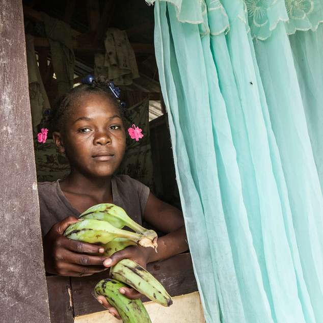 Haiti: Hilfe für Menschen in Not. Ein Kind reicht Bananen aus einem Fenster.
