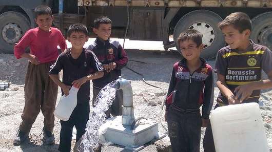 Kinder holen im Irak Wasser von einer Wassertränke.