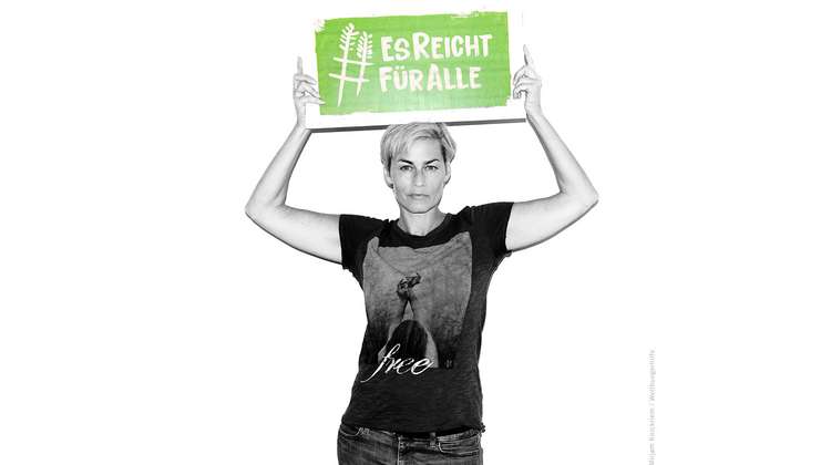 Schauspielerin Gesine Cukrowski hält ein Schild mit dem Welthungerhilfe-Hashtag #EsReichtFürAlle.