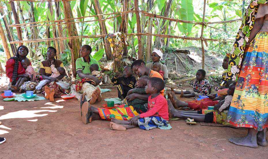 Mehrere Frauen und Kinder sitzen auf dem Boden und essen.