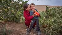 Evin, 23, erntet mit ihrem kleinen Sohn selbst angebaute Tomaten im Irak
