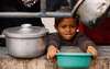 Ein kleines Kind hält eine Schüssel mit ausgestreckten Armen und wartet auf die Verteilung von Essen