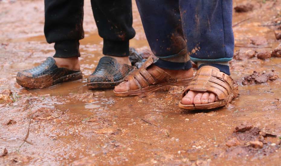 Kinder mit Sandalen im Schlamm, Syrien 2019.
